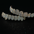 Set of grillz fully covered in sparkling stones and gold‑tone metal.