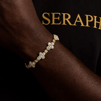 Slim chain bracelet with a small cross charm encrusted in stones.